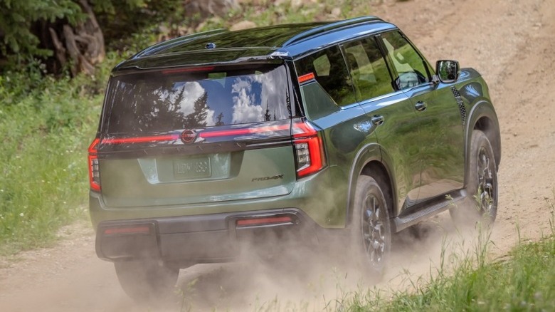 2025 Nissan Armada PRO-4X driving on dirt road next to trees