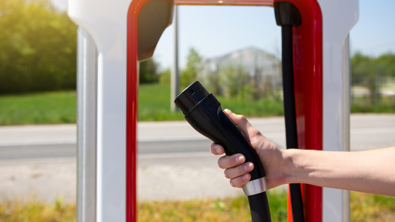 Hand holding Tesla Supercharger connector