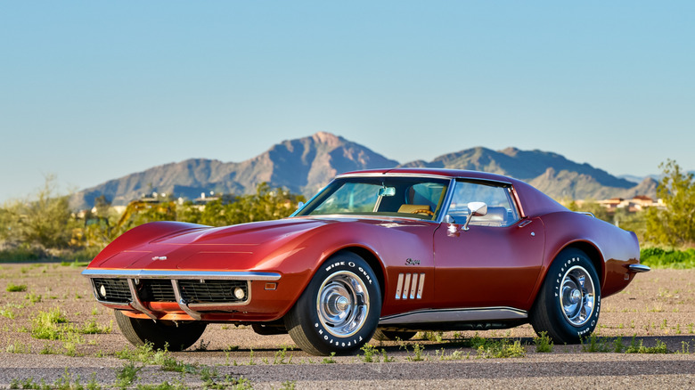 Red 1969 Chevy Corvette front side view parked on dirt on a sunny day