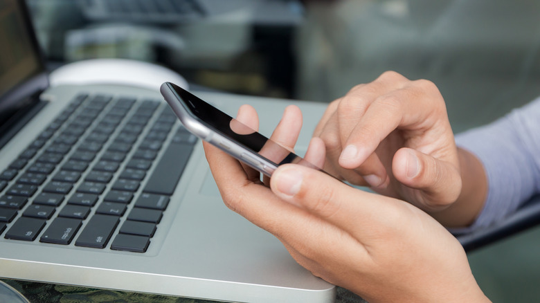 person using iphone over macbook