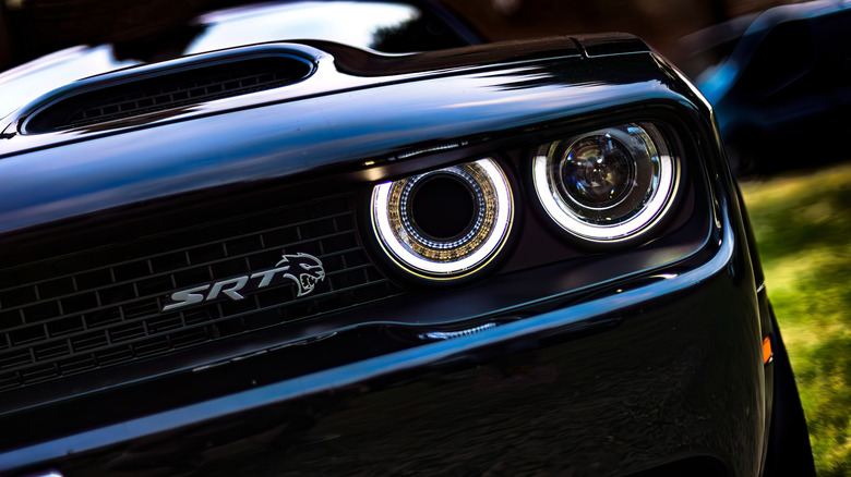 The front headlights of a black Dodge Challenger SRT Hellcat.