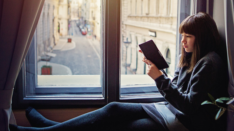 person reading ebook in window sill