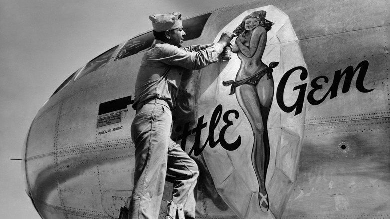 Crewman painting a pinup on an aircraft