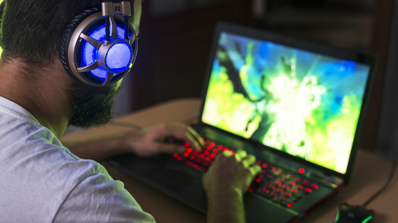 Person playing on gaming laptop with headphones