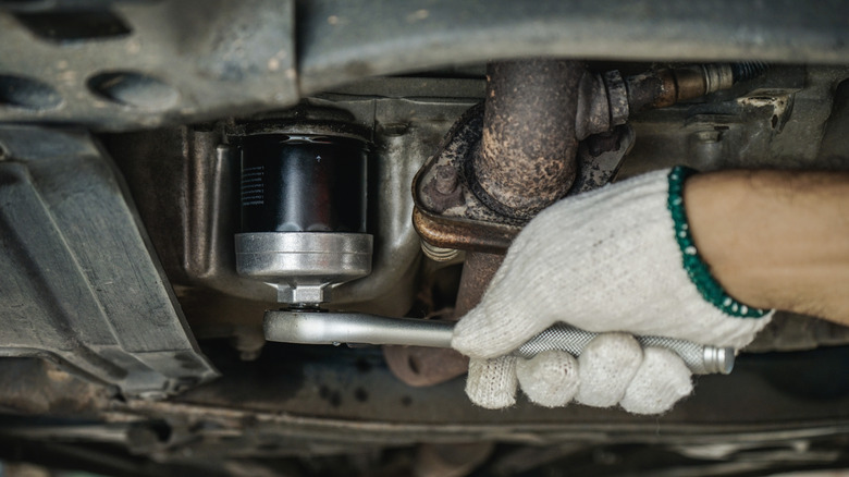 Mechanic using a wrench to remove oil filter