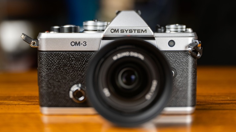 The OM System OM-3 on top of a wooden table.