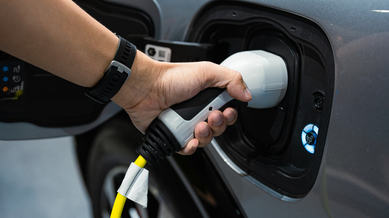 Man plugging in charging station to car close up