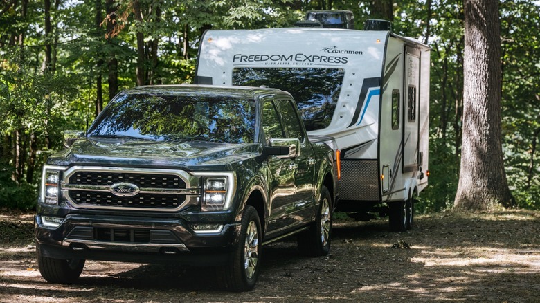 Ford F-150 parking a travel trailer in a campsite.