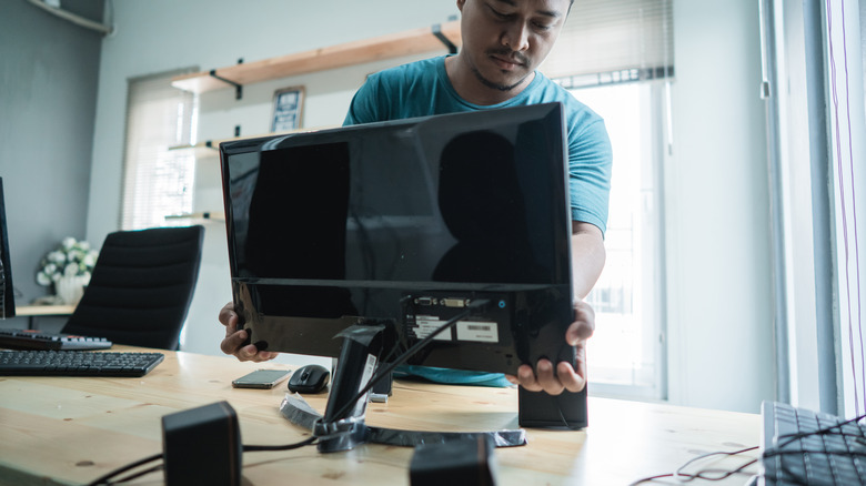 A man adjusting computer monitor in office