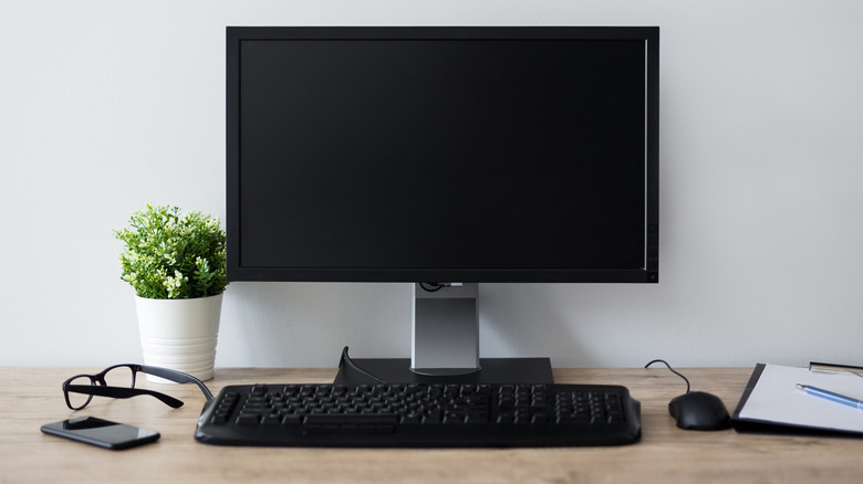 Wooden table with computer monitor with glasses and plants