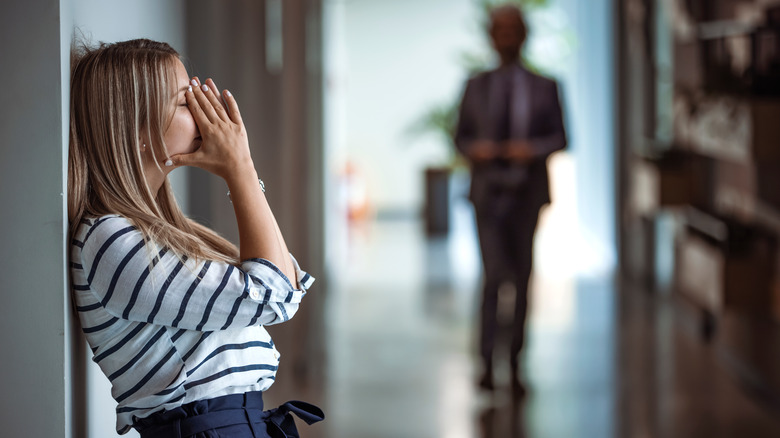 Woman leaning against the wall in frustration over sexism at her job.