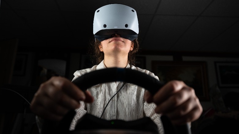Person wearing PlayStation VR2 with steering wheel