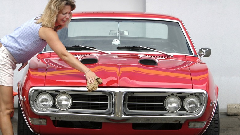 Lady cleans red 1968 Pontiac Firebird