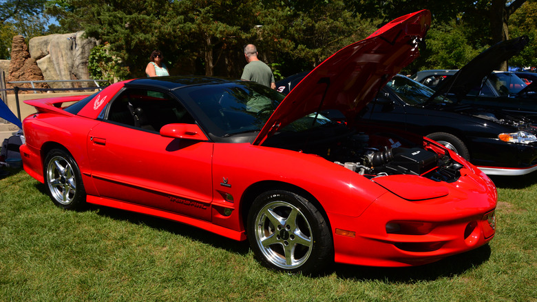 Red Pontiac Firebird parked with hood open