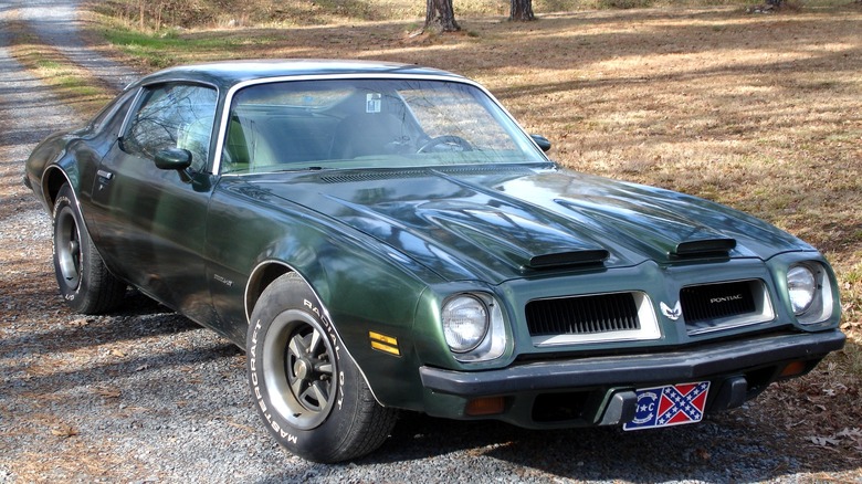 Green 1974 Pontiac Firebird parked on gravel