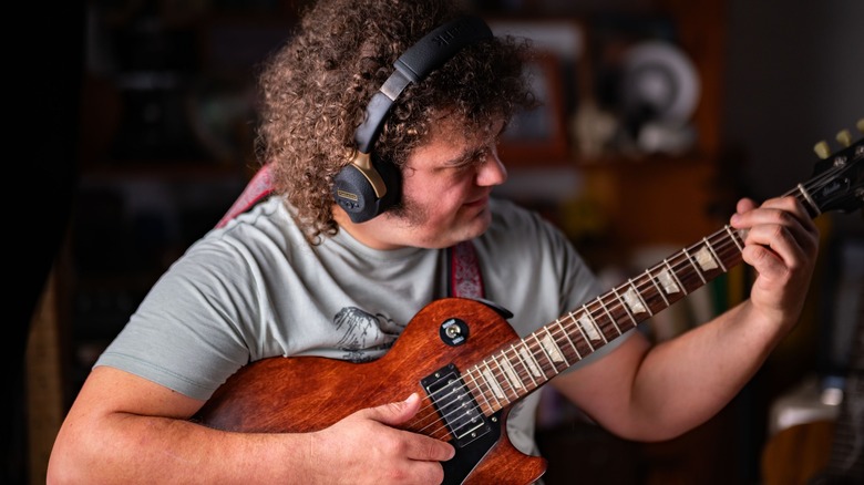 Andy Zahn playing a Gibson Les Paul guitar while wearing the Positive Grid Spark Neo.