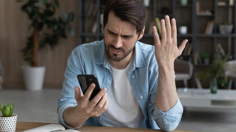 man annoyed by smartphone