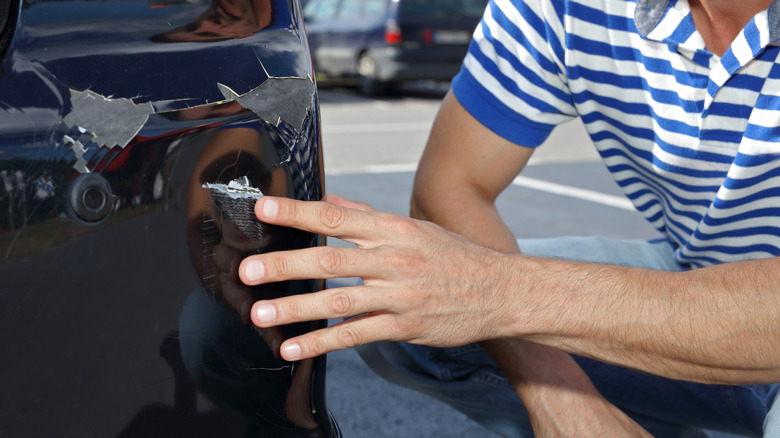 Man looking at dent in car