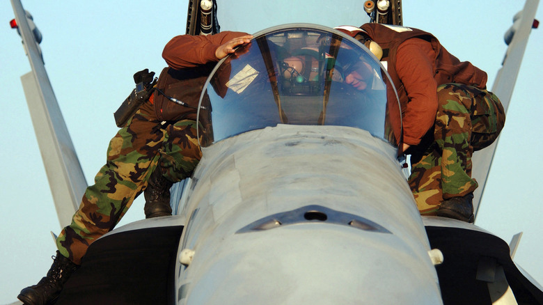 Two brown shirts conducting pre-flight checks on an F/A-18C Hornet