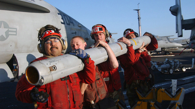 Red shirts lifting an AMRAAM missile
