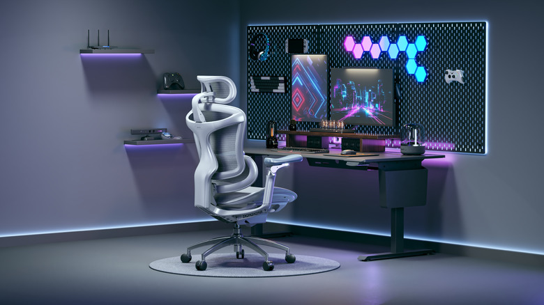 A Sihoo Doro C300 Pro at a sleek workspace with multiple flatscreens, headphones, gaming systems, and neon-colored ambient lighting.