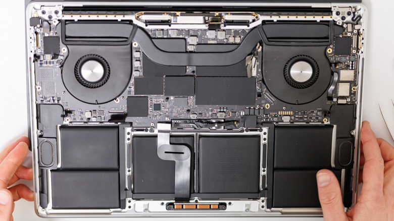 A person repairing the innards of a Macbook.