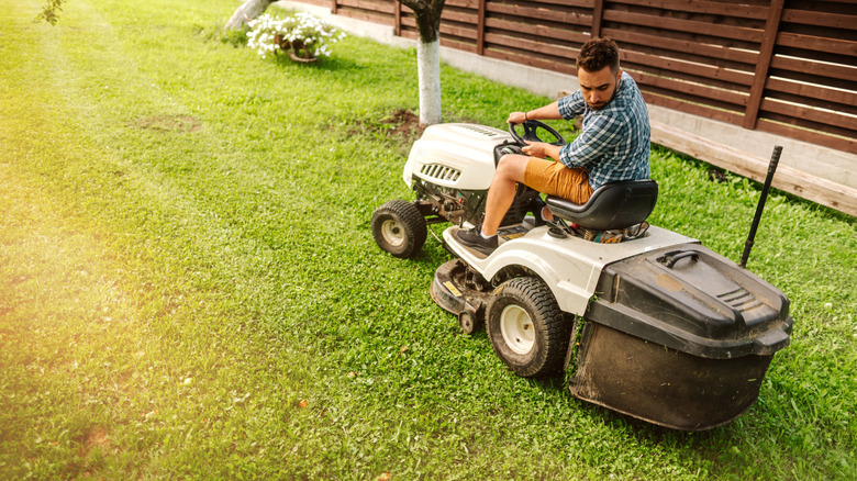 Man on white lawn tractor in yard