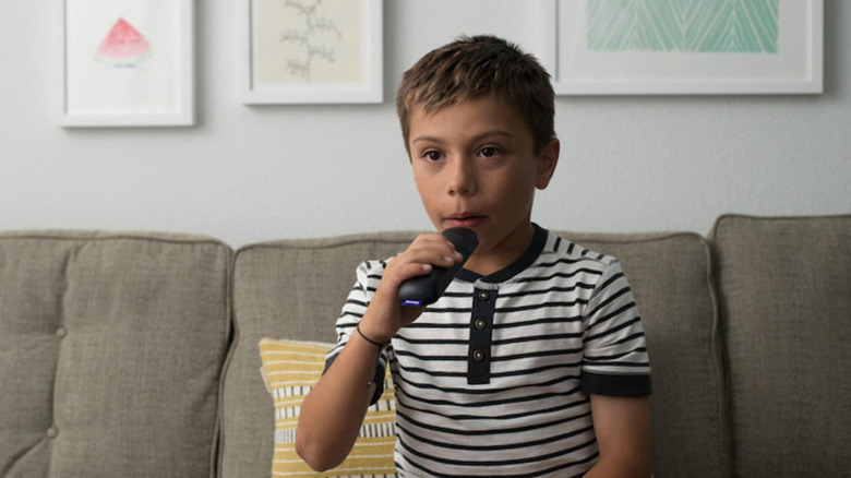 A child holding a Roku remote and speaking into it