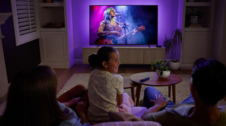 Family of three watching a woman singing on the TV