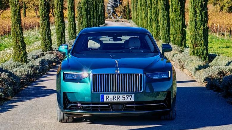 Front view of a Rolls-Royce ghost series II flanked by trees