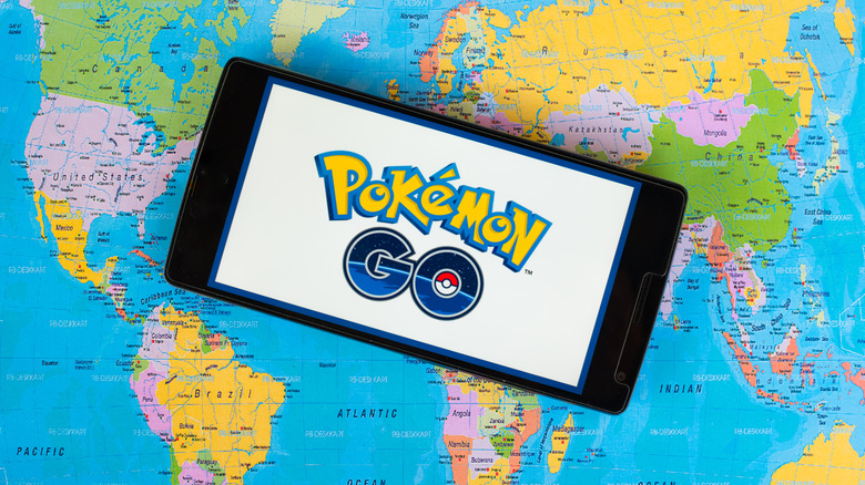 Pokemon GO logo displayed on smartphone laid out on world map