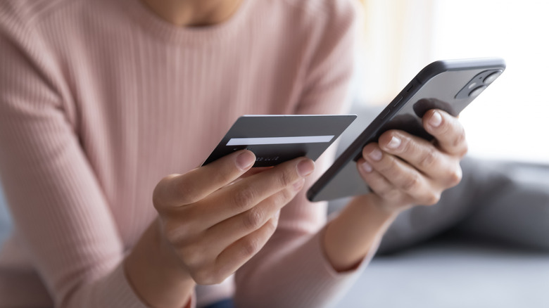 Woman holding credit card and phone