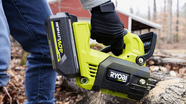 Man cutting log with chainsaw powered by 40V Ryobi battery