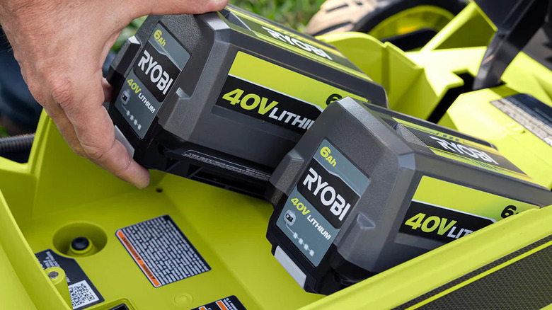 Hand placing two Ryobi 40V batteries next to each other