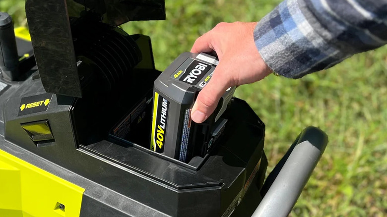 Hand putting Ryobi 40V battery into outdoor power tool