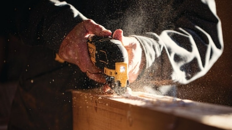 Person using DeWalt oscillating tool on lumber