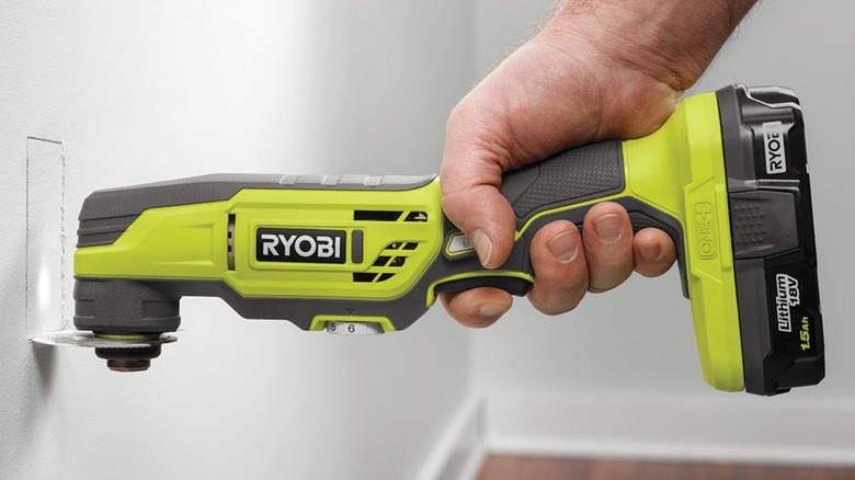 Person using Ryobi oscillating tool on drywall