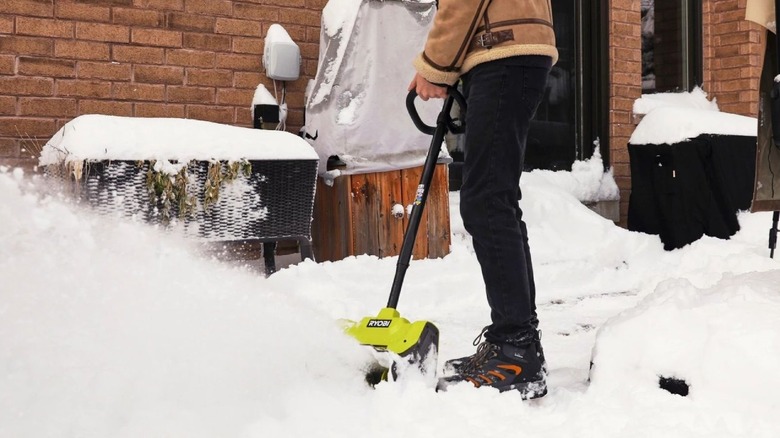 Person using an electric snow shovel to clear snow