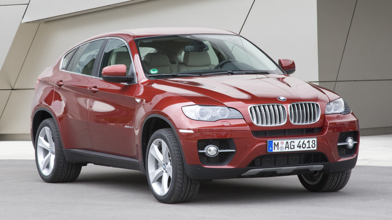 Front 3/4 view of red 2008 BMW X6 parked in front of building