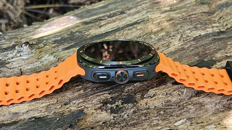 Samsung Galaxy Watch Ultra with its orange band on a log