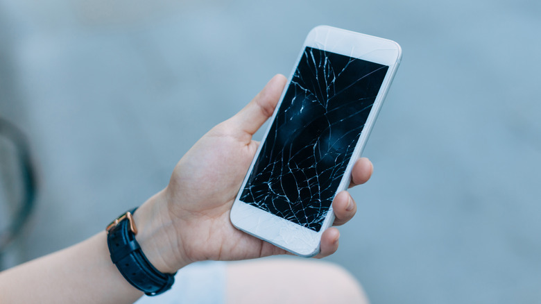 Woman holding smartphone with a cracked screen