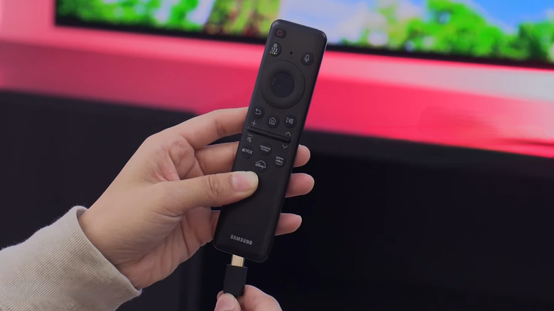 A person inserting USB C charging cable on the Samsung TV remote