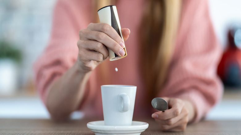 Person adding saccharin in coffee cup