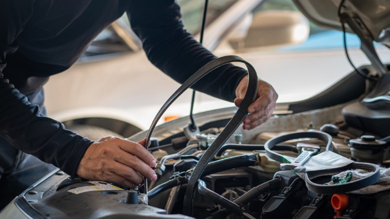 person replacing serpentine belt