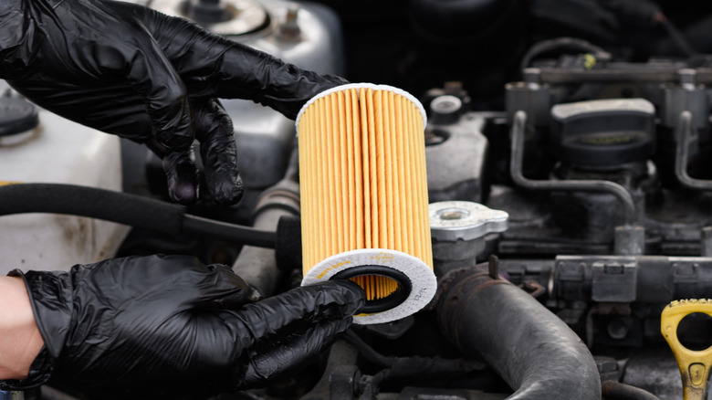 Mechanic changing oil filter in car