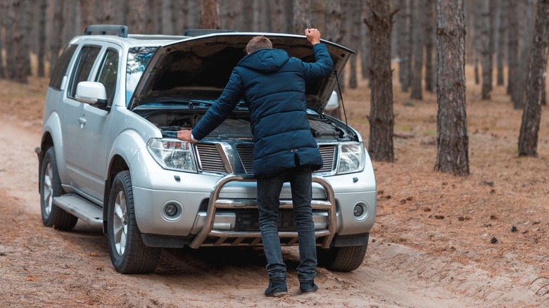 Person in forest with broken vehicle