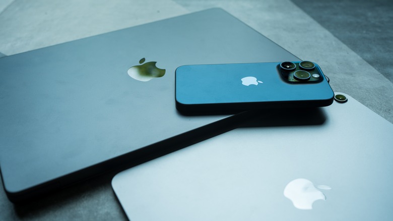 The iPad Air M2 and Macbook Pro with iPhone 15 Pro sit on the Macbook body.