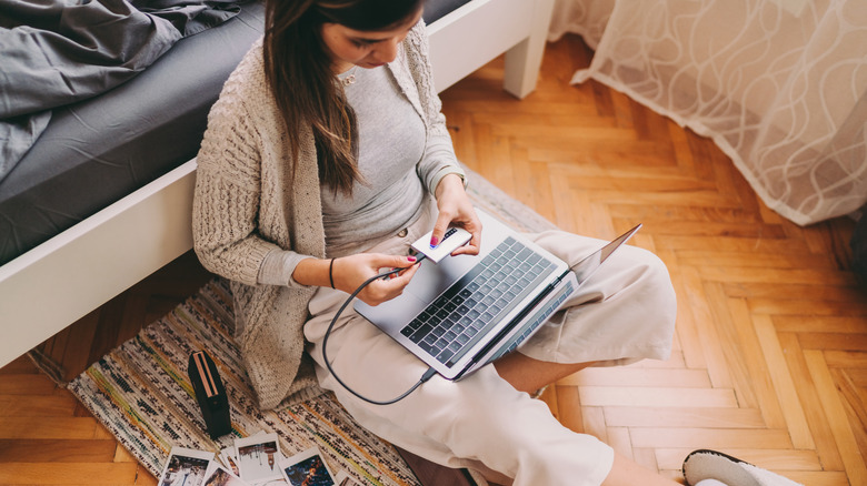 woman plugging external hard drive into computer