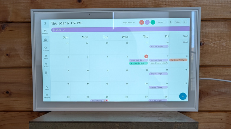 Skylight Calendar display the monthly view layout, on a small wooden shelf against a wood panelled wall.