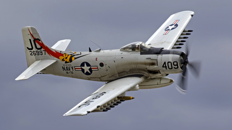 An A-1 Skyraider flying at the 2017 Planes of Fame Air Show in Chino, California, over grey, cloudy skies.